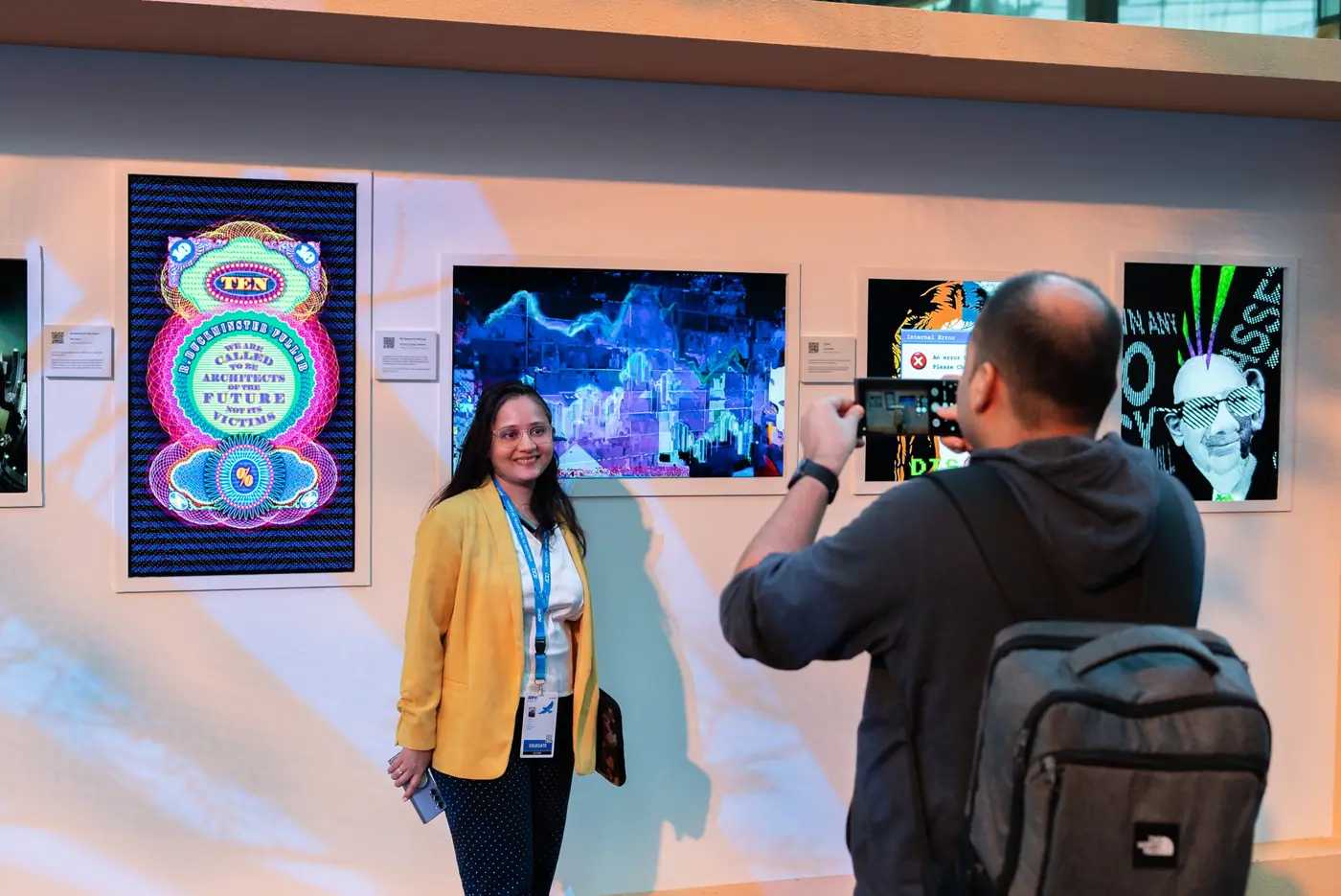 A delegate posing for a photo in front of digital artworks