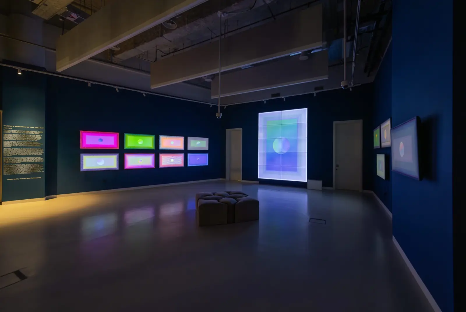 Blue gallery with a grid of eight screens and a large LED wall