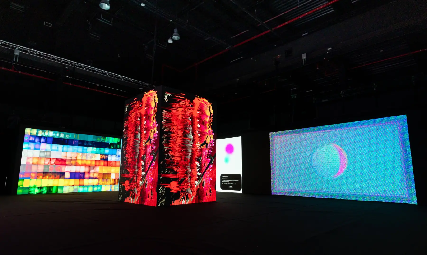Wide view of Outliers: a central LED column surrounded by oversized LED walls