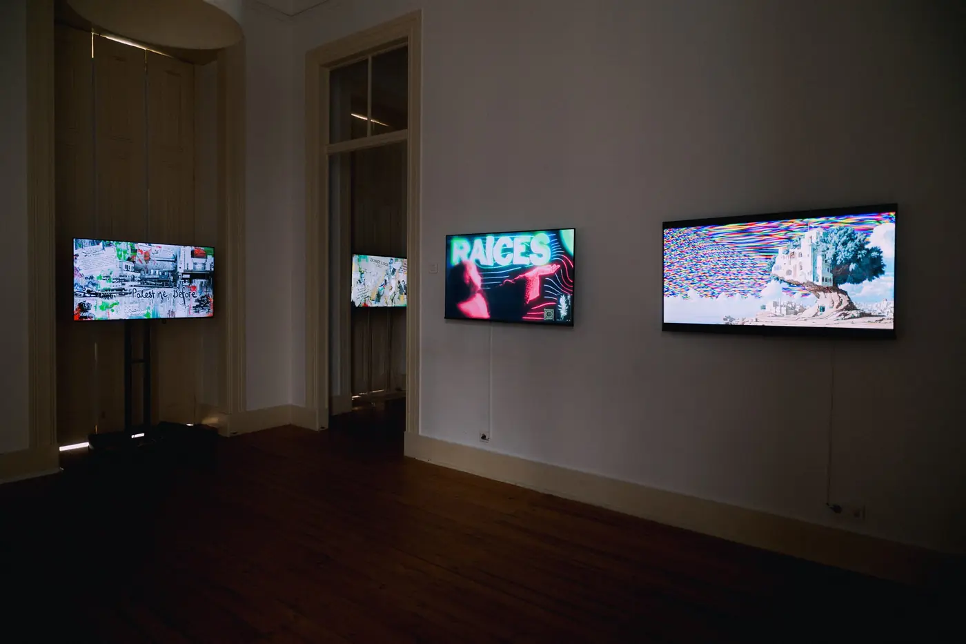 A room with four screens, one on a stand and three on the walls