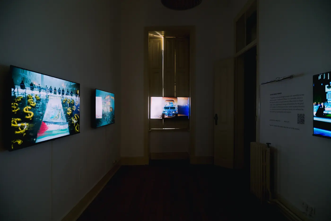 A narrow room with screens and wall text